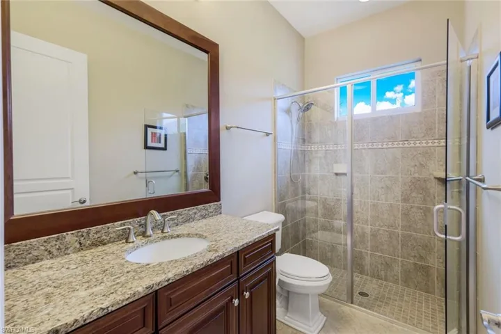 Bathroom featuring toilet, vanity, and a stall shower