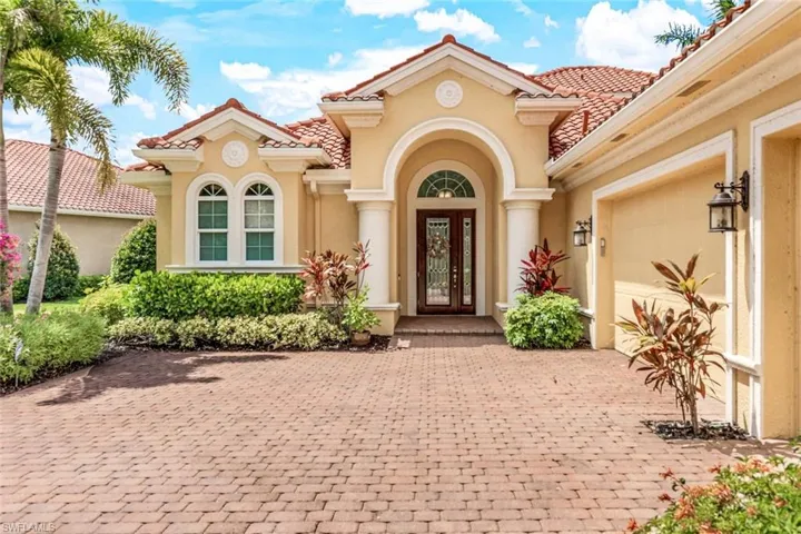 Entrance to property featuring stucco siding, a garage, a tiled roof, and decorative driveway