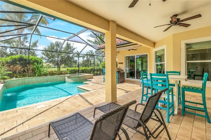 View of pool with a ceiling fan, a pool with connected hot tub, glass enclosure, and a patio