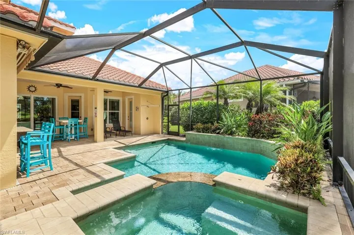 View of swimming pool featuring ceiling fan, a lanai, a pool with connected hot tub, and a patio