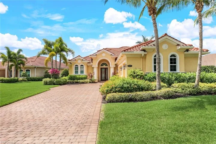 Mediterranean / spanish house featuring stucco siding, a front lawn, a tiled roof, and decorative driveway