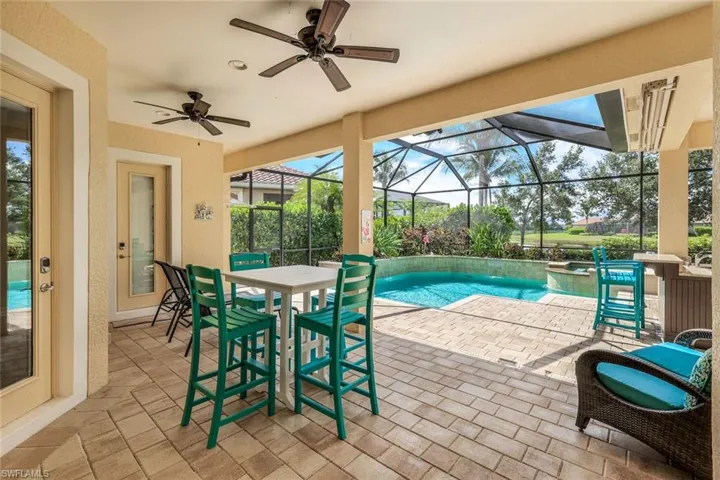 View of swimming pool featuring glass enclosure, a pool with connected hot tub, a patio, and a ceiling fan