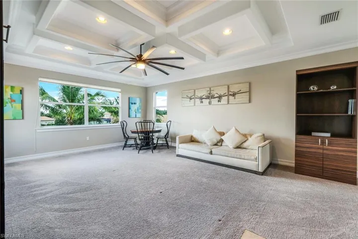 Living room with carpet flooring, visible vents, ornamental molding, a ceiling fan, and coffered ceiling