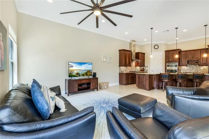 Living room with baseboards, ceiling fan, visible vents, and ornamental molding