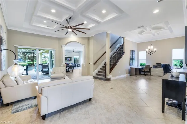 Living room with coffered ceiling, stairway, ceiling fan with notable chandelier, a towering ceiling, and a wealth of natural light