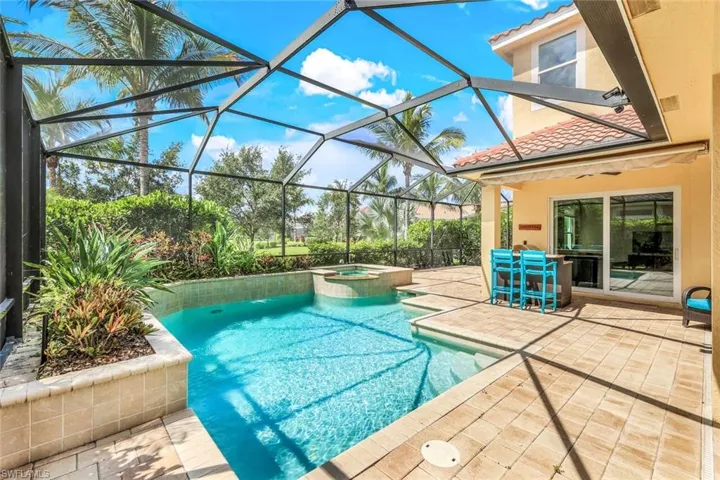 View of swimming pool featuring glass enclosure, ceiling fan, a pool with connected hot tub, and a patio area