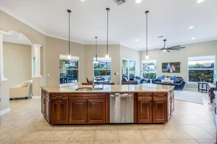 Kitchen featuring decorative columns, a sink, a ceiling fan, dishwasher, and open floor plan