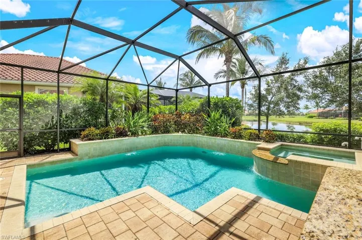 View of pool with a pool with connected hot tub, a lanai, a water view, and a patio