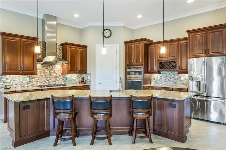 Kitchen with stainless steel appliances, ornamental molding, a sink, a kitchen island with sink, and wall chimney exhaust hood