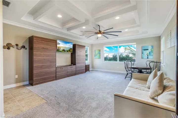 Living room with coffered ceiling, light colored carpet, visible vents, and crown molding