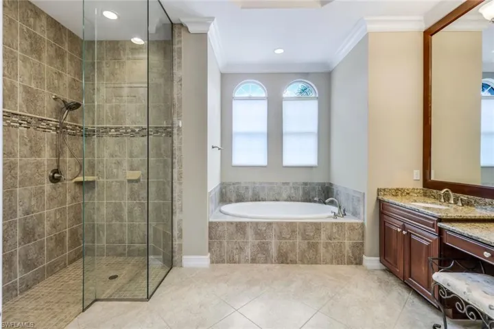 Full bathroom with vanity, ornamental molding, tiled shower, and a bath