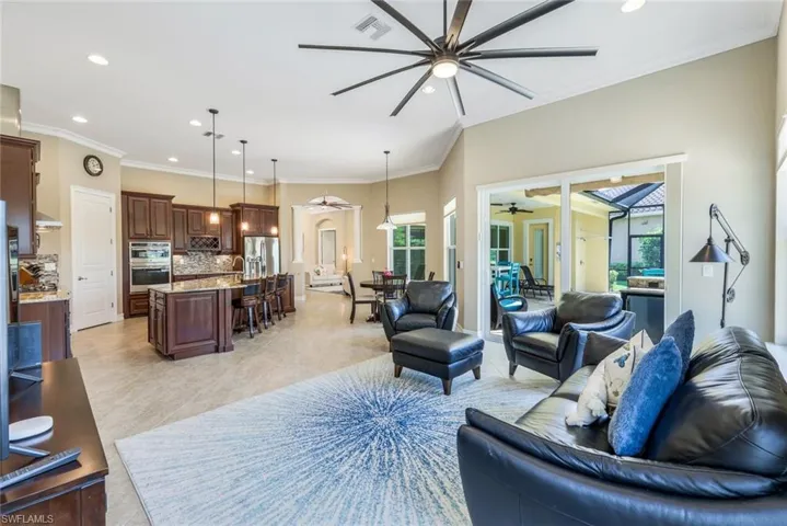 Living room with light tile patterned floors, a wealth of natural light, crown molding, and ceiling fan