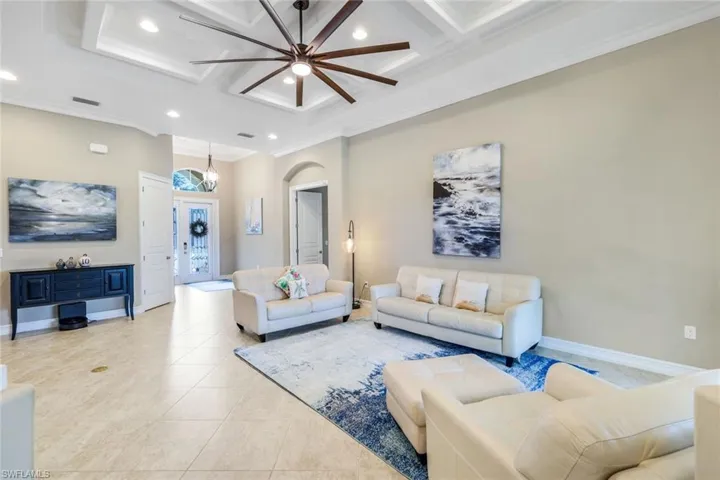 Living room featuring coffered ceiling, recessed lighting, baseboards, light tile patterned flooring, and ceiling fan