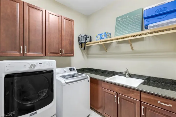 Washroom with washing machine and dryer, cabinet space, and a sink