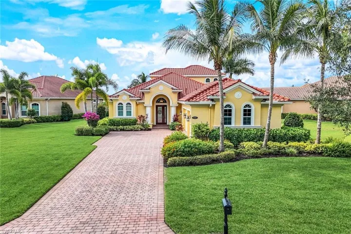 Mediterranean / spanish house with a tile roof, decorative driveway, stucco siding, and a front lawn