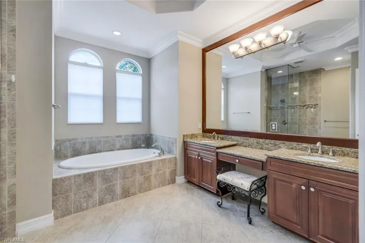 Full bath featuring a sink, a bath, crown molding, and a shower stall