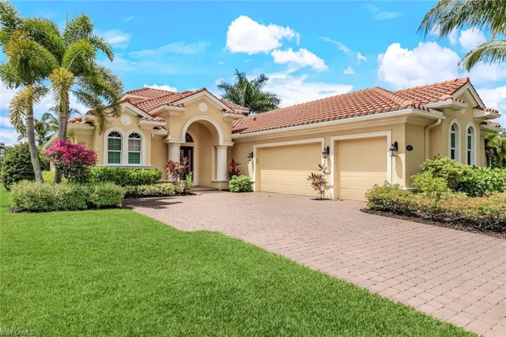 Mediterranean / spanish house with a tile roof, stucco siding, an attached garage, a front lawn, and decorative driveway