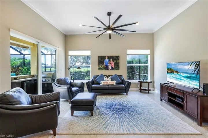 Living area featuring light tile patterned flooring, baseboards, ceiling fan, and ornamental molding