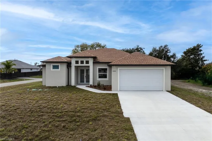 Prairie-style house with driveway, stucco siding, a front yard, a garage, and a shingled roof