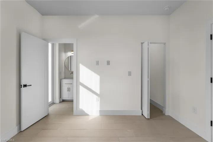 Unfurnished bedroom with ensuite bath and light wood finished floors