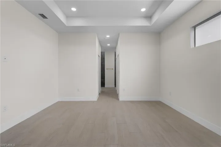 Spare room featuring light wood finished floors, recessed lighting, and a raised ceiling