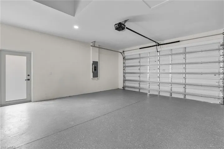 Garage with recessed lighting, a garage door opener, and electric panel