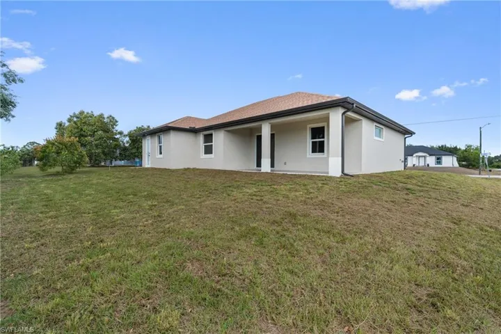 Back of house with a lawn, stucco siding, and a patio