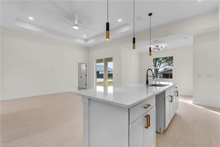 Kitchen featuring open floor plan, light stone countertops, pendant lighting, light wood-type flooring, and recessed lighting