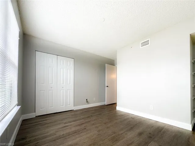 Unfurnished bedroom featuring dark wood finished floors, a closet, and a textured ceiling