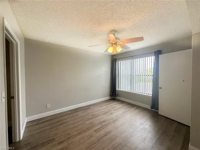 Spare room with a textured ceiling, wood finished floors, and ceiling fan