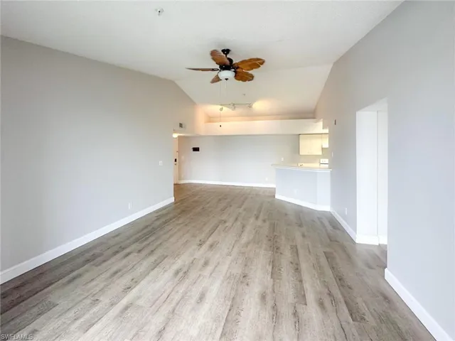 Unfurnished living room with lofted ceiling, light wood-style flooring, and ceiling fan