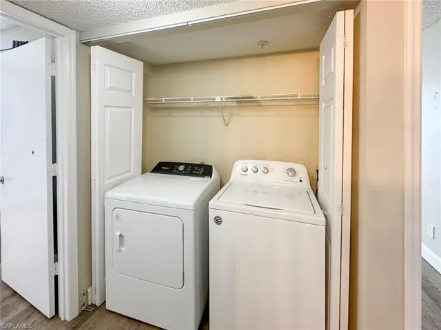 Laundry area with light wood-style flooring, a textured ceiling, and washer and dryer