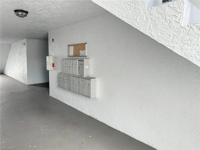 Detailed view of a textured wall, mail area, a textured ceiling, and concrete flooring