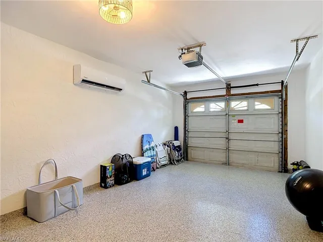 Garage featuring a split air conditioning unit, light fixture, and a durable speckled epoxy floor coating