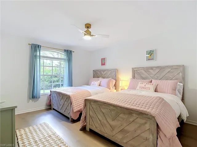 Wood-finish flooring, gold-tone ceiling fan, and arched window with white muntins