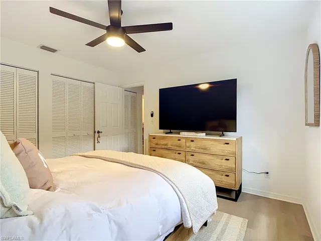 White louvered bi-fold closet doors, wood-finish flooring, and a ceiling fan with integrated lighting