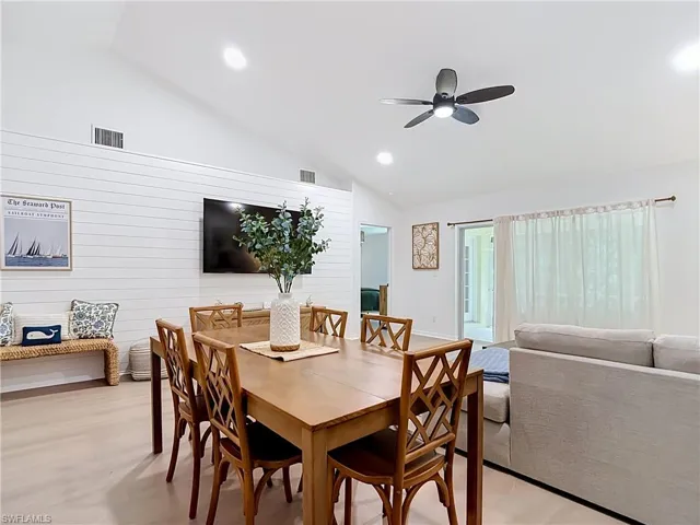 Vaulted ceiling with recessed lighting and a ceiling fan, shiplap accent wall, wood-finish flooring, and sliding glass doors