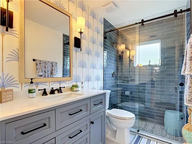 Modern bathroom featuring a single vanity with stone countertop, gray cabinetry, and black fixtures