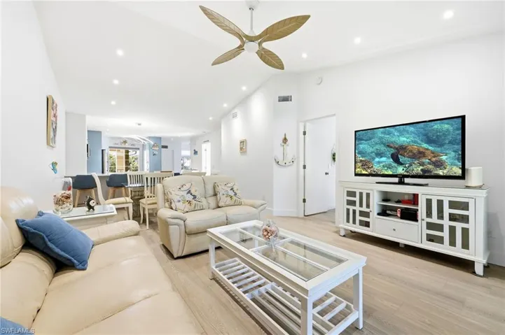 Living area with light wood finished floors, high vaulted ceiling, recessed lighting, and ceiling fan