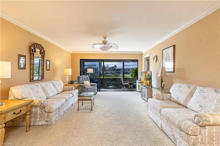 Living room with light colored carpet, plenty of natural light, crown molding, and ceiling fan