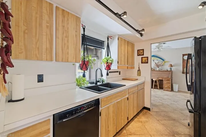 Kitchen with black appliances, a sink, light countertops, and ceiling fan