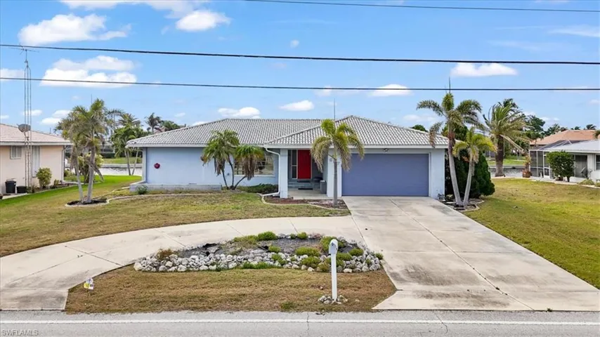 View of front of property with a tile roof, curved driveway, a front lawn, and an attached garage