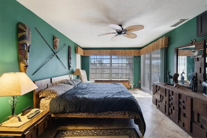 Tiled bedroom with multiple windows, a textured ceiling, and ceiling fan
