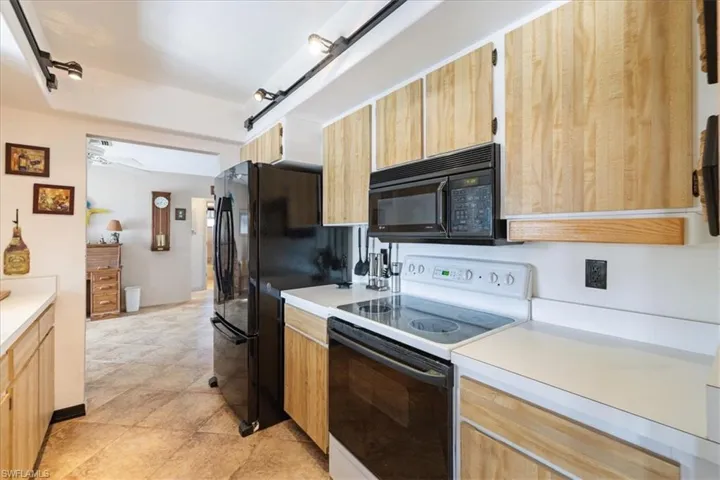 Kitchen with black appliances, light countertops, and light brown cabinets