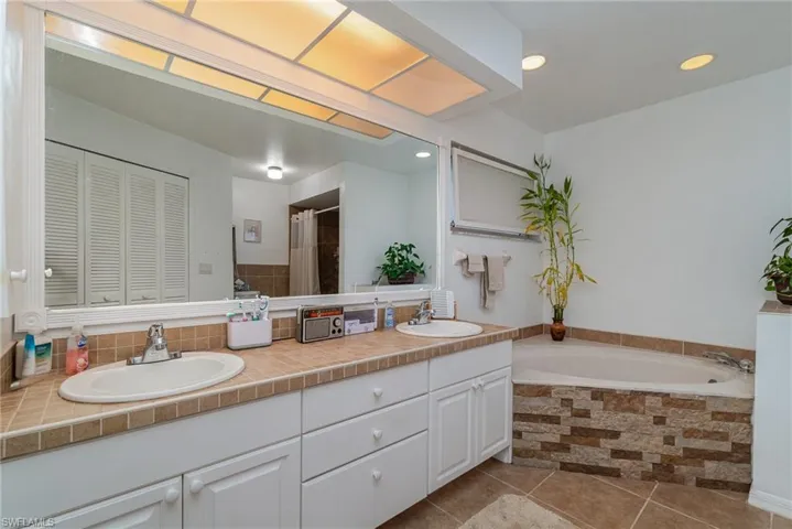 Bathroom featuring tile patterned flooring, vanity, and tiled tub