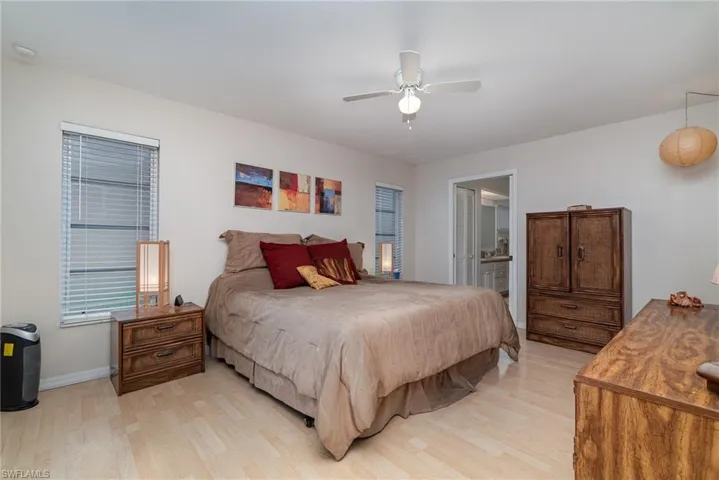 Bedroom featuring light hardwood / wood-style flooring, ceiling fan, and ensuite bathroom