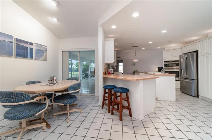 Kitchen with white cabinetry, decorative light fixtures, appliances with stainless steel finishes, a kitchen breakfast bar, and kitchen peninsula
