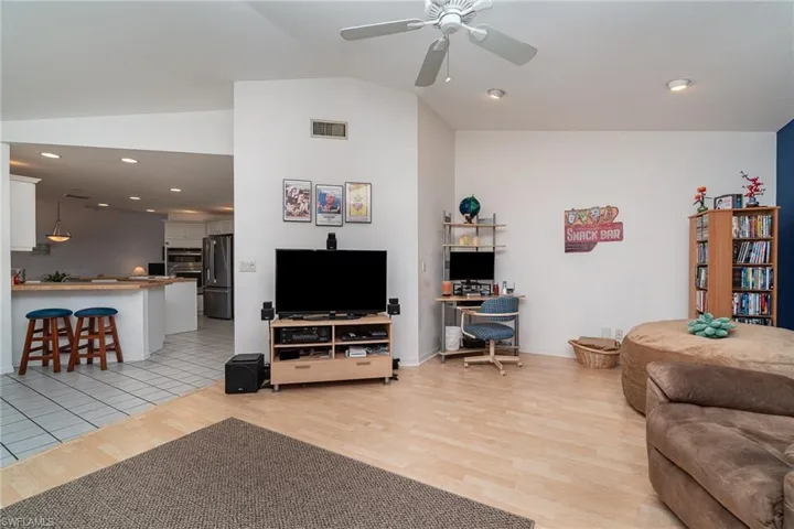 Living room featuring ceiling fan, lofted ceiling, and light hardwood / wood-style floors