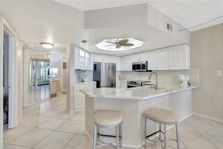 Kitchen with stainless steel appliances, white cabinetry, a peninsula, a kitchen breakfast bar, and backsplash