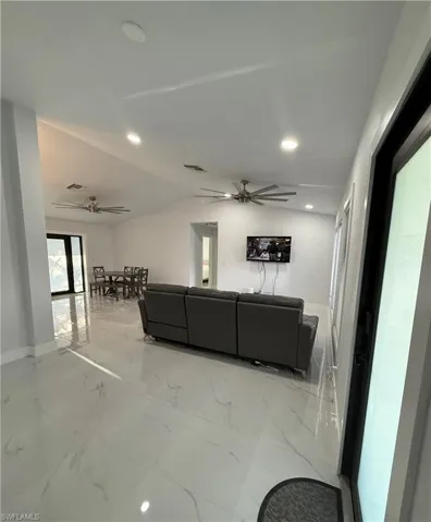 Living area with light marble finish floors, a ceiling fan, vaulted ceiling, and recessed lighting